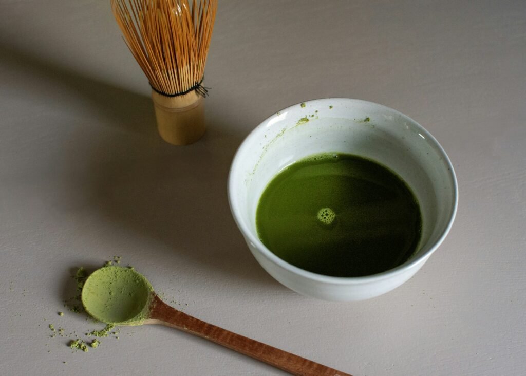 Current image: a bowl of green liquid next to a whisk